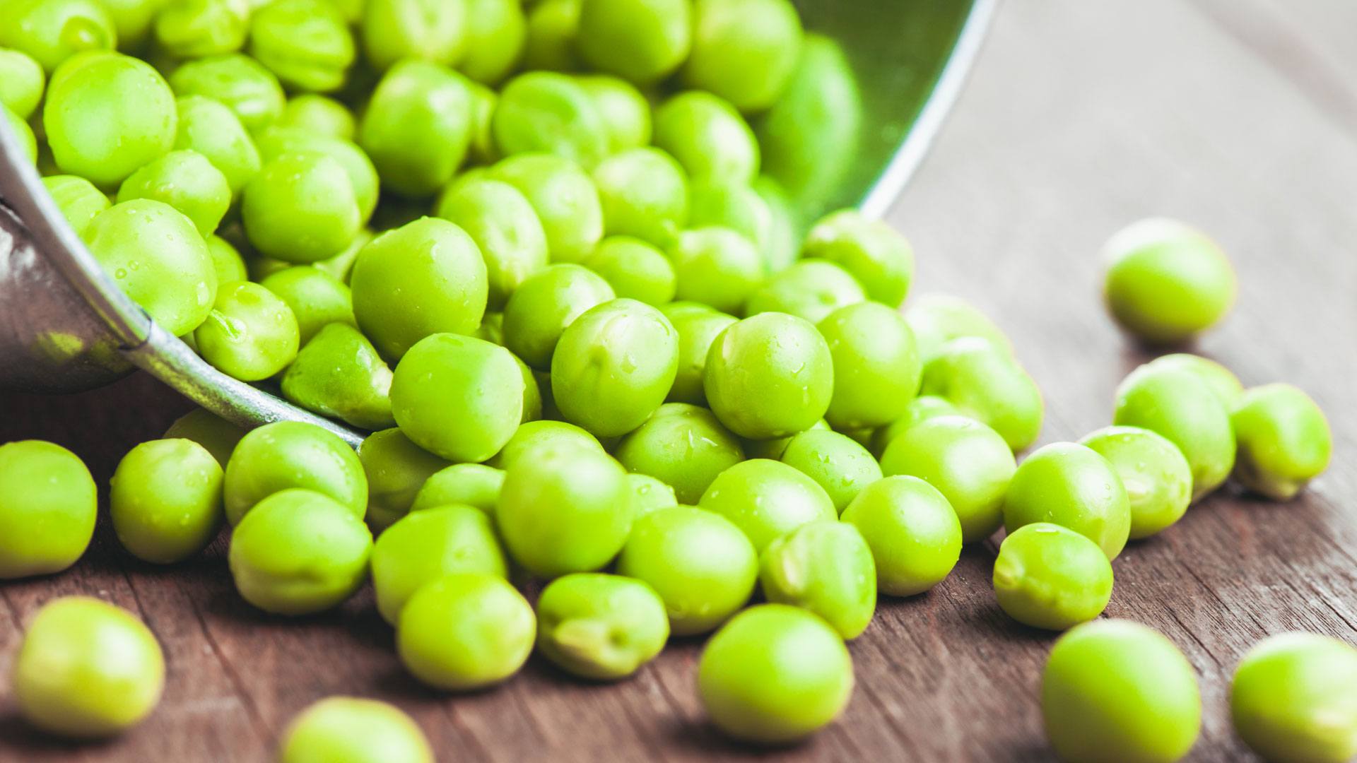 A bunch of peas pour out of a jar onto a table. Pea protein is a higher quality than most realize.