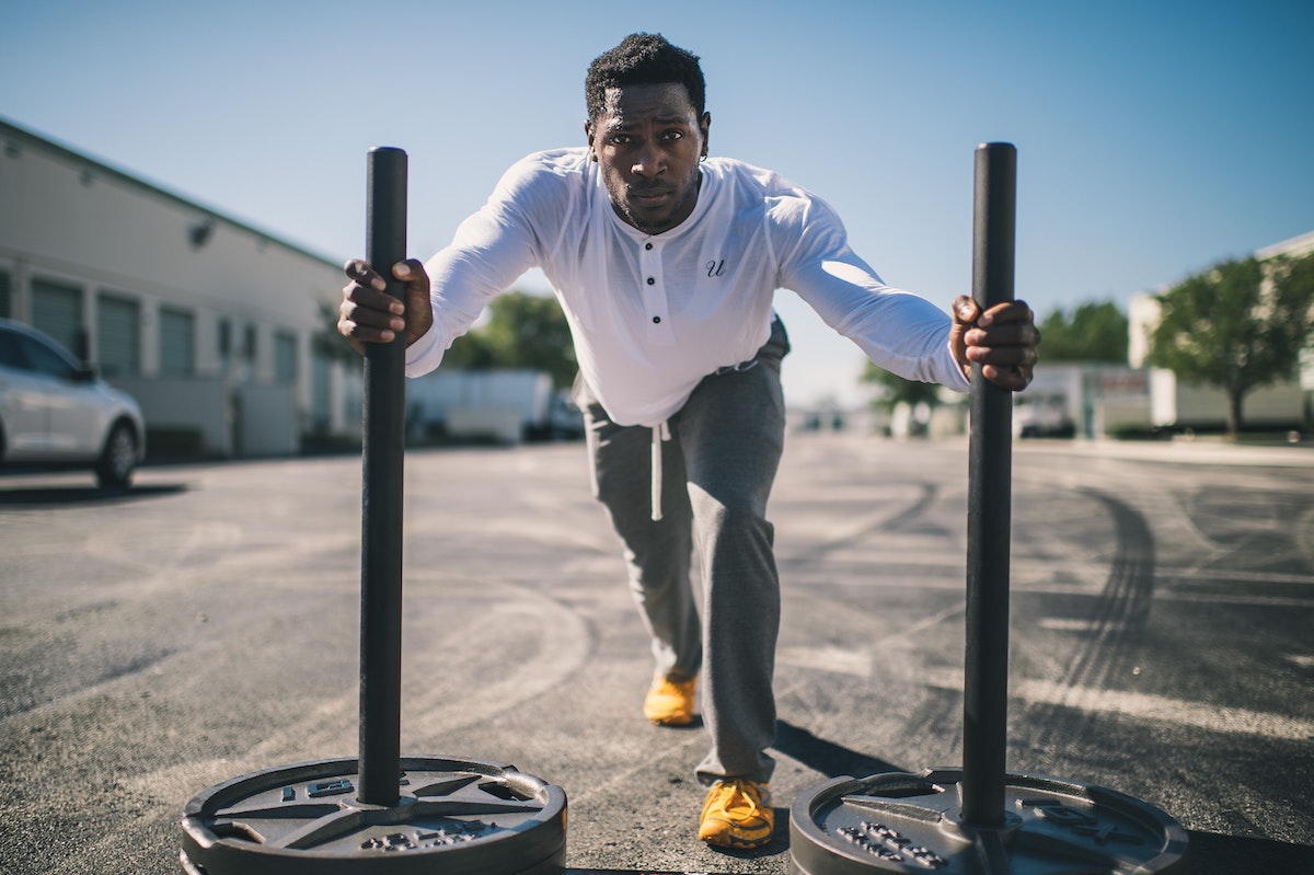 Man Wearing White Long-sleeved Shirt Pushing Two Weight Sleds