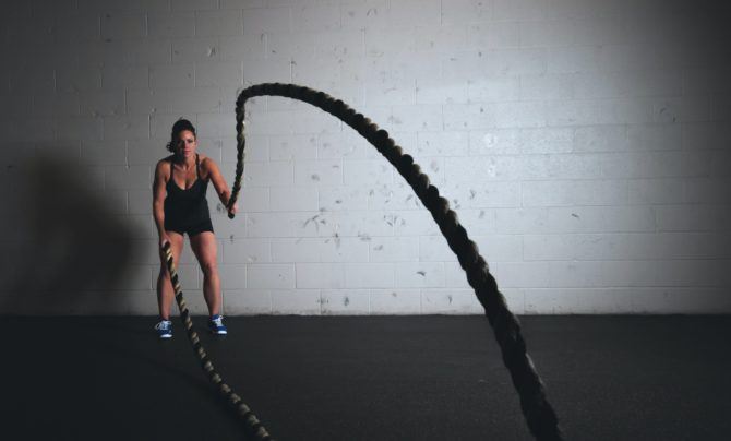 Woman performs high intensity battle ropes exercise