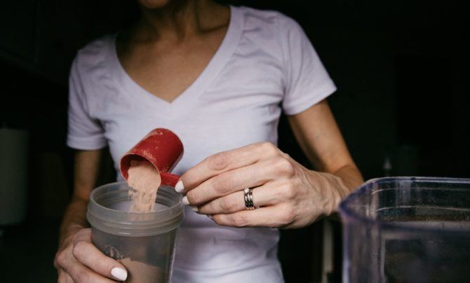 Pouring protein shake powder into a cup