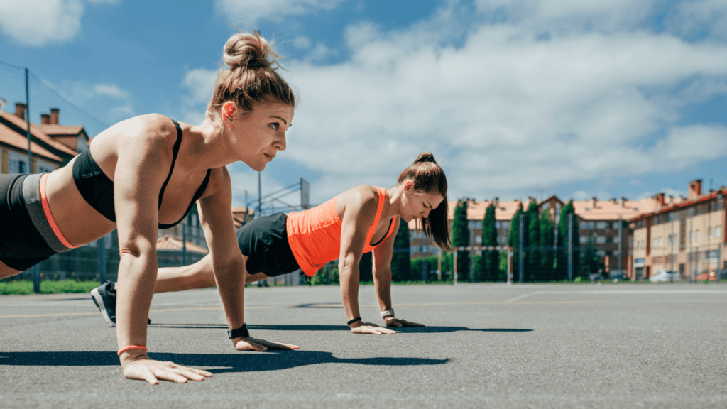 two women doing pushups outside