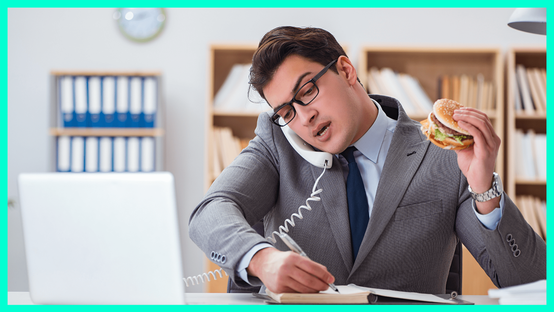 man eating a burger while working