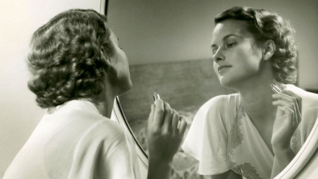 woman looking in mirror and putting on lipstick