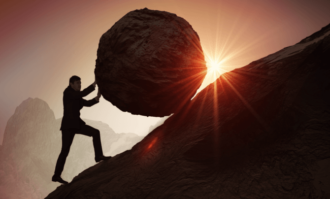 man in a suit pushing a boulder uphill