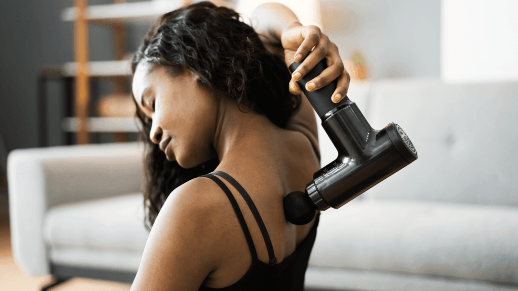 woman using a massage gun on her back